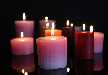 Many burning small candles on dark background, close-up