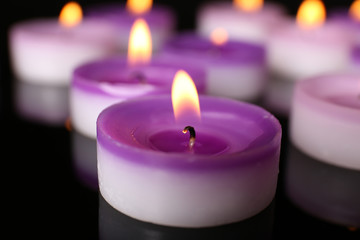 Many burning small candles on dark background, close-up