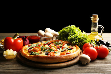 Delicious pizza with vegetables on black background