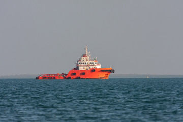 Orange rescue ship sails across the bay at sunset.