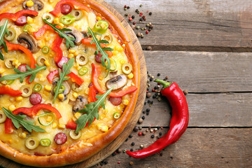 Delicious pizza with pepper on wooden background