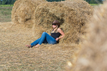 Naklejka na ściany i meble Pretty young girl on a haystack
