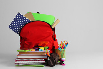 Backpack with school supplies on wooden table