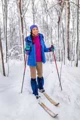 Poster smiling young woman skier in winter forest