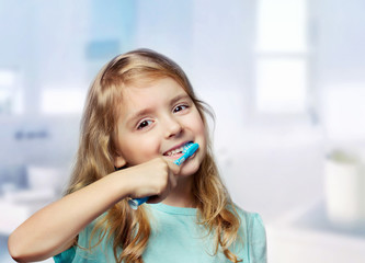 Child girl toddler cleaning teeth in bathroom background.