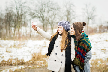 Fototapeta na wymiar Two girlfriends taking a selfie in winter