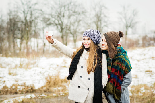 Two girlfriends taking a selfie in winter