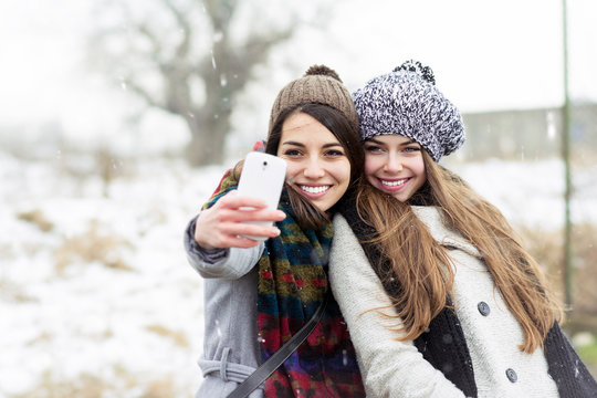 Two teenage girlfriends taking a selfie in winter