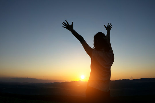 silhouette woman Hands up against sunset