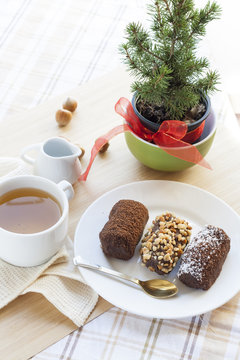 Fresh hot green tea in white cup with chocolate cakes in basket.