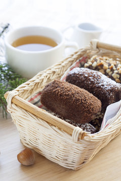 Fresh hot green tea in white cup with chocolate cakes in basket.