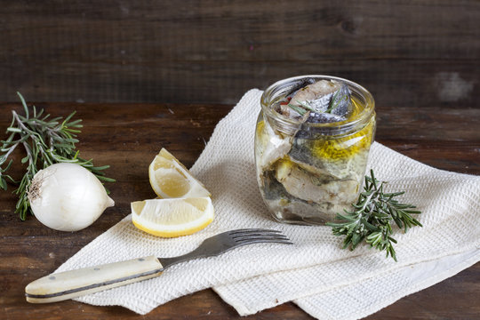 Preserved marinated sliced fish in a glass jar.