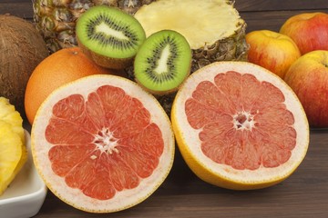 Red grapefruit and fruit for weight loss. Fresh dietary food for athletes. Fruit on a wooden table. Composition with variety of fresh fruits. Balanced diet. Assortment of exotic fruits. 
