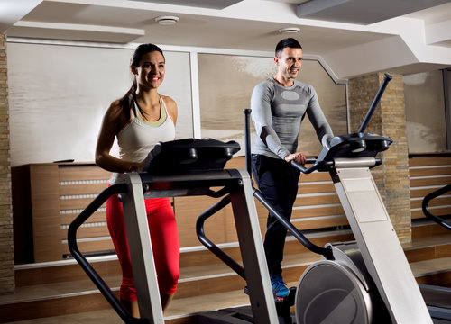 Young people on exercise machine in gym doing cardio