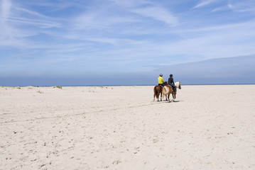 Two people on horses on the beach at the North Sea in Norderney, Germany