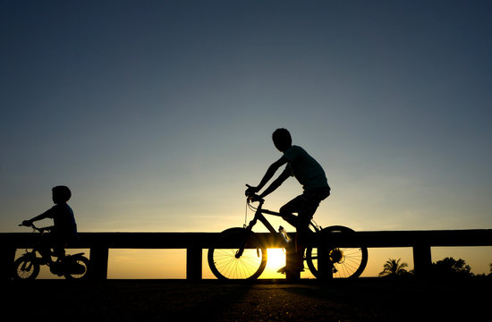Silhouette motion cyclist bicycles against sunset