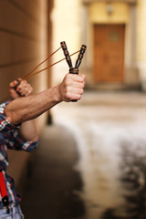 Человек стреляет из рогатки на улице