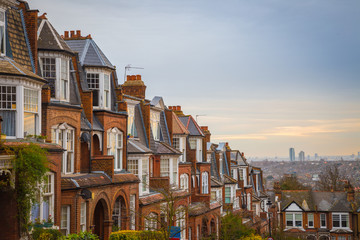 Traditional British brick houses on a cloudy morning with east London at background. Panoramic shot...