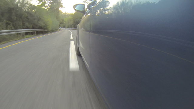 Car mounted POV shot of a blue car driving on a curved road