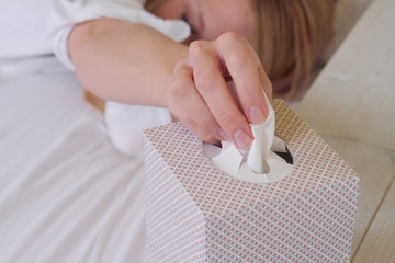 Woman caught cold , flue, running nose, selective  focus on hand and  tissue box