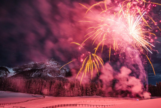Gro&szlig;es Feuerwerk mit Personen, schaulustigen Fotografen, vor den Bergen im Winter und im Schnee