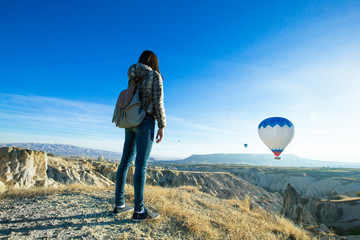 Female tourist taking photos of hot air balloon in Cappadocia