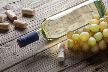 Glass bottle of wine with corkscrew on wooden table background