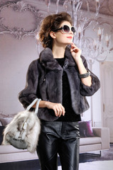 fashion model in autumn/winter clothes wearing sunglasses holding bag posing 