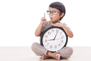 Cute boy is holding big clock with finger up.
