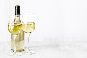 Bottle of vine and two glass wine are stand on the white tablecl