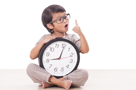 Cute boy is holding big clock with finger up.