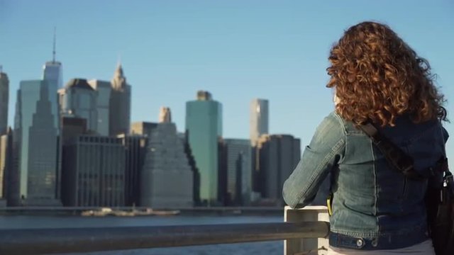A woman takes pictures of NYC skyline.