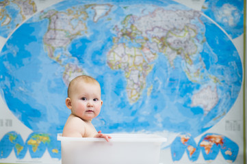 Baby sitting in a box, on a background map
