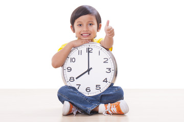 Cute boy is holding big clock and showing thumb up.
