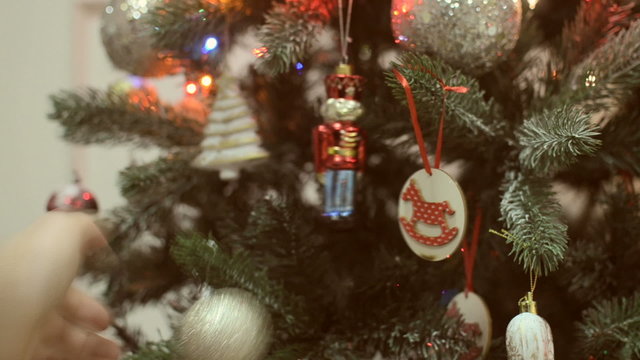 Man's hand shakes Christmas toys on the Christmas tree.