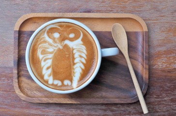 Latte Coffee art "Owl" and wood spoon on the wood saucer.