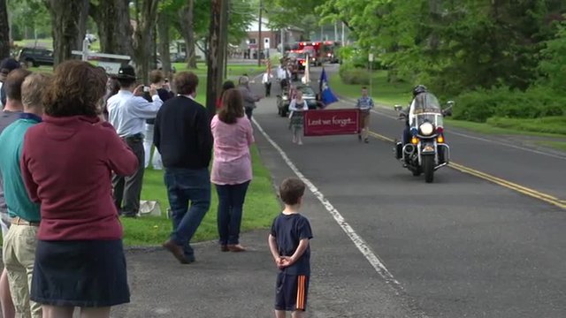 Residents watch a parade in a quaint New England town.
