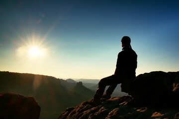 Obraz premium Hiker take relaxing on a rock and enjoying sunset at horizon. Vivid effect.