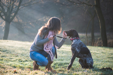 Brunette woman posing with her adorable German pointer dog outdoor