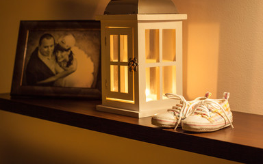 Children's shoes, photograph the bride and groom and lantern on the shelf. Retro scene.