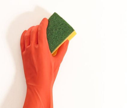 Mano con guante sujetando una esponja de limpieza.