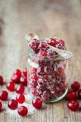 Fresh ripe cranberries with sugar in glass jar. Selective focus.