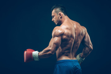 Muscular boxer in studio shooting, on black background.