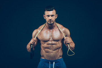 Fototapeta na wymiar Muscular man skipping rope. Portrait of muscular young men exercising with jumping rope on black background