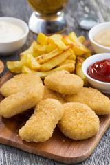 chicken nuggets with french fries and tomato sauce on board