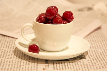 Frozen red cherries in a white cup.