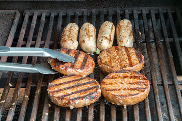 Burgers and sausages cooking on a gas barbecue