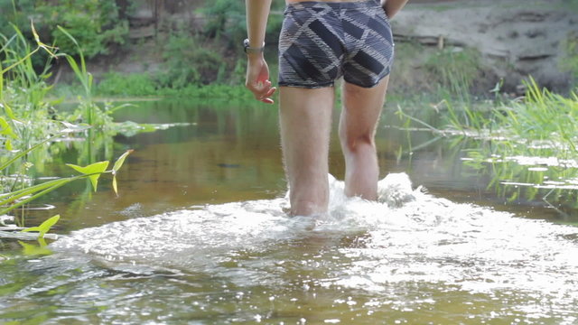 A man walks into the water of the river.