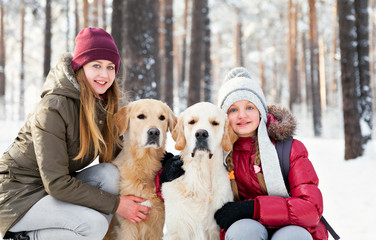 Walking the dog in the park in winter. Two sisters