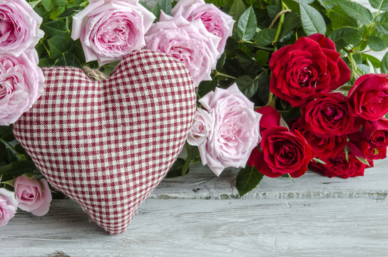 Checked handmade heart against of red and pink roses